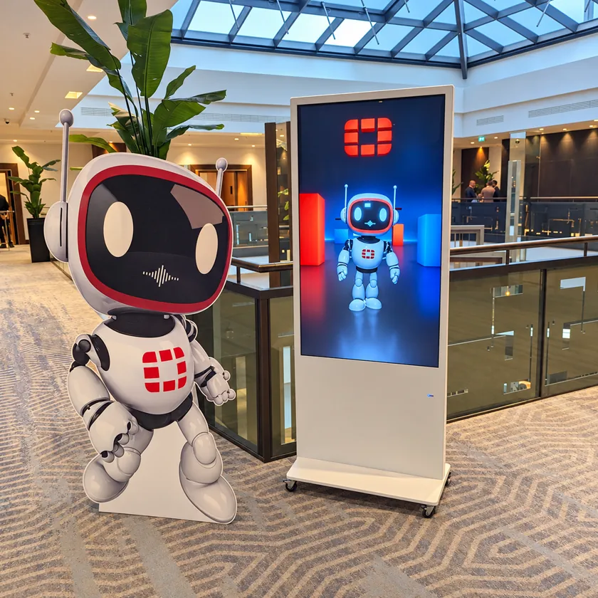 Portrait digital totem at a conference showing an animated 3D mascot character beside event schedule information